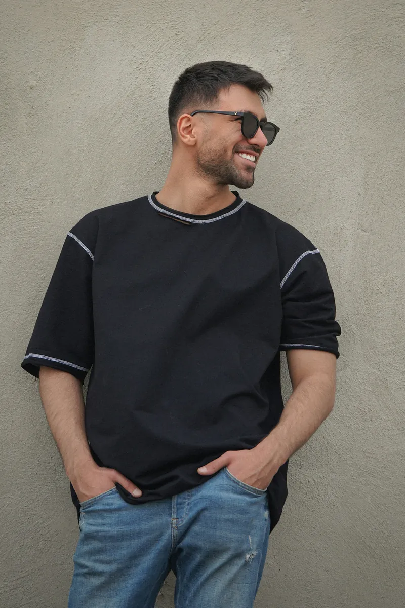 Junger Mann im schwarzen Shirt vor einer hellen Wand